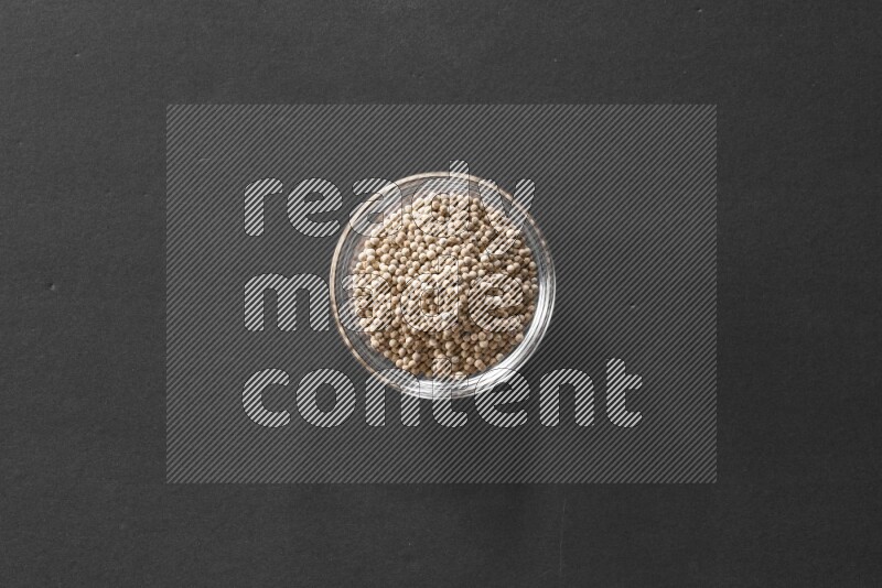A glass bowl full of white peppers on black flooring