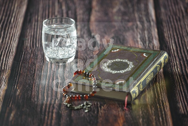 Quran with dates, prayer beads and different drinks all placed on wooden background