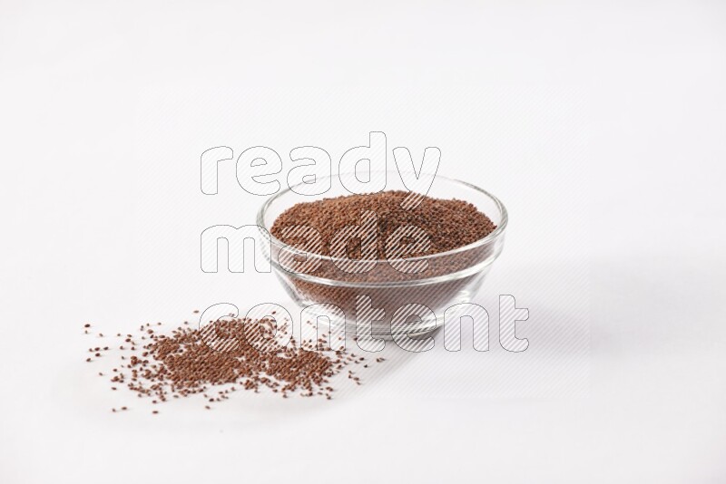 A glass bowl full of garden cress seeds with more seeds spread on a white flooring