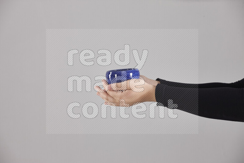 A woman in black abaya holding different pottery essentials in different positions