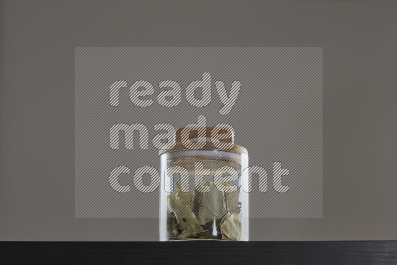 Bay laurel leaves in a glass jar on black background