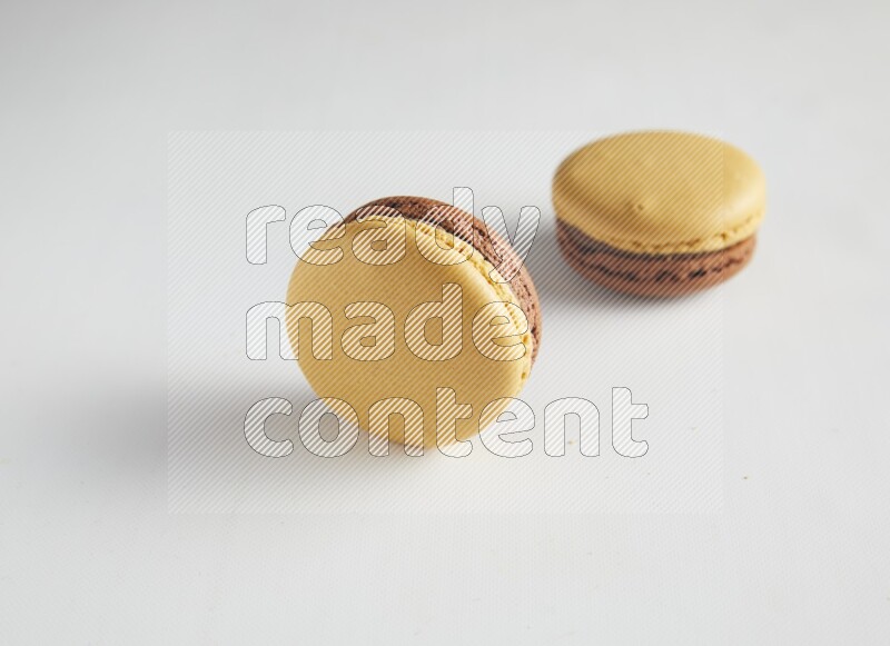 45º Shot of two Yellow and Brown Chai Latte macarons on white background