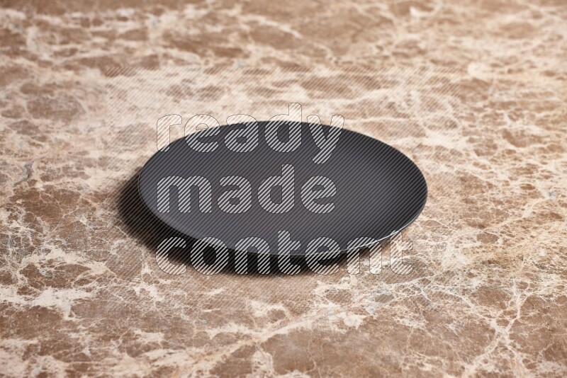 A black ceramic circular plate on beige marble background