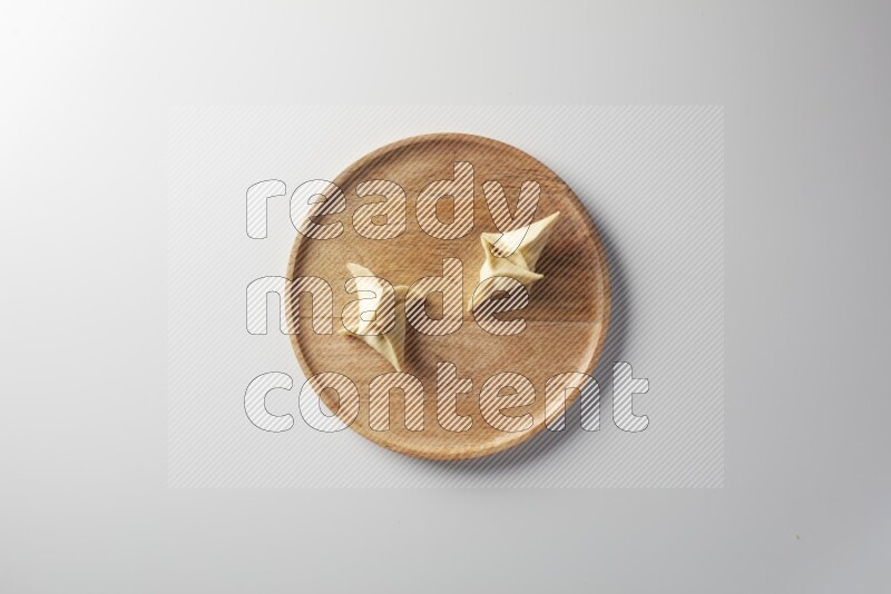 Four Sambosas on a wooden round plate on a white background