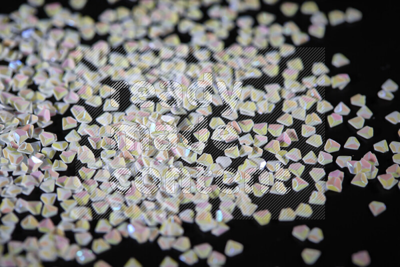 قطع صغيرة بلاستيكية ملونة للزينة متناثرة على خلفية سوداء