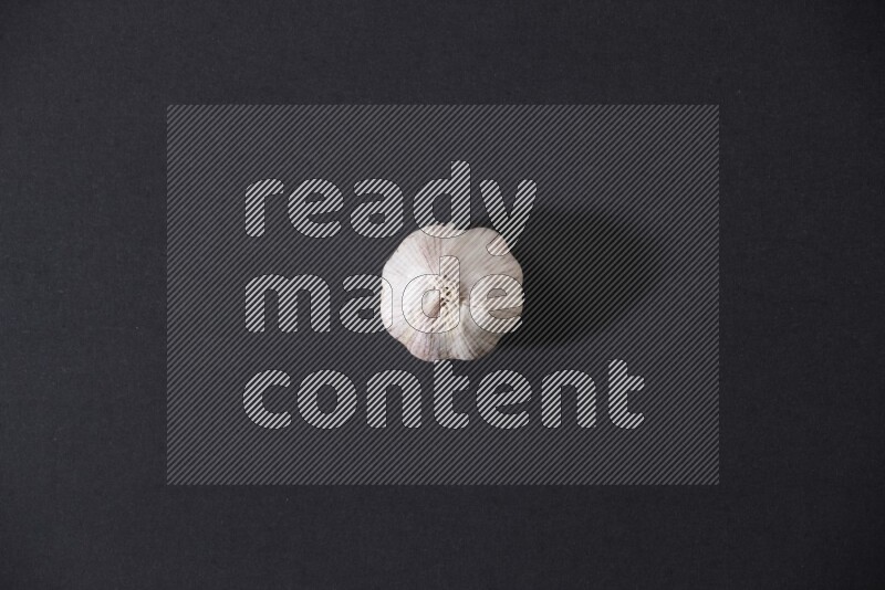 A whole garlic bulb placed on a black flooring