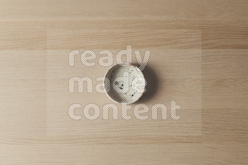 A multicolored pottery bowl on light wooden background