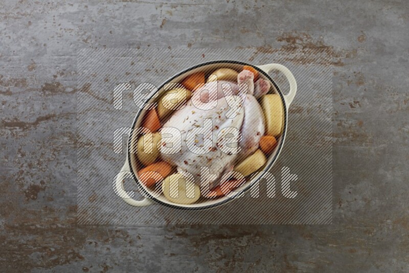 whole raw chicken on in a white ceramic pot direct on a rustic grey background