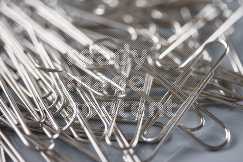 Silver paper clips isolated on a grey background