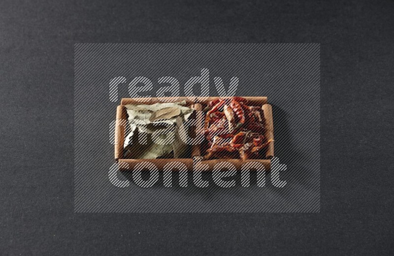 2 squares of cinnamon sticks full of chilis and bay laurel leaves on black flooring