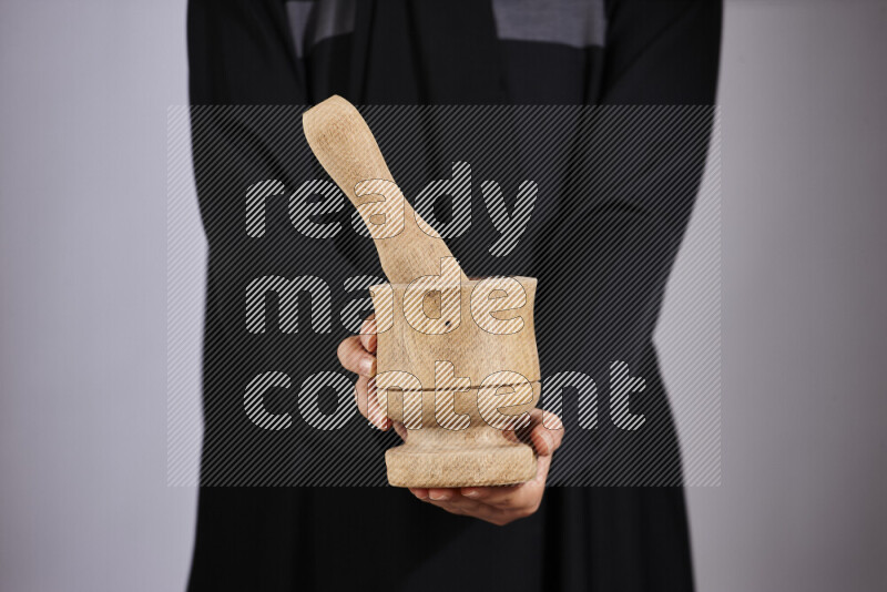 A woman in black abaya holding different wooden essentials in different positions