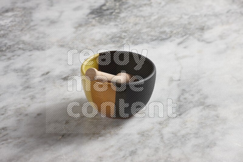 Multicolored pottery bowl with wooden honey dipper in it on grey marble background