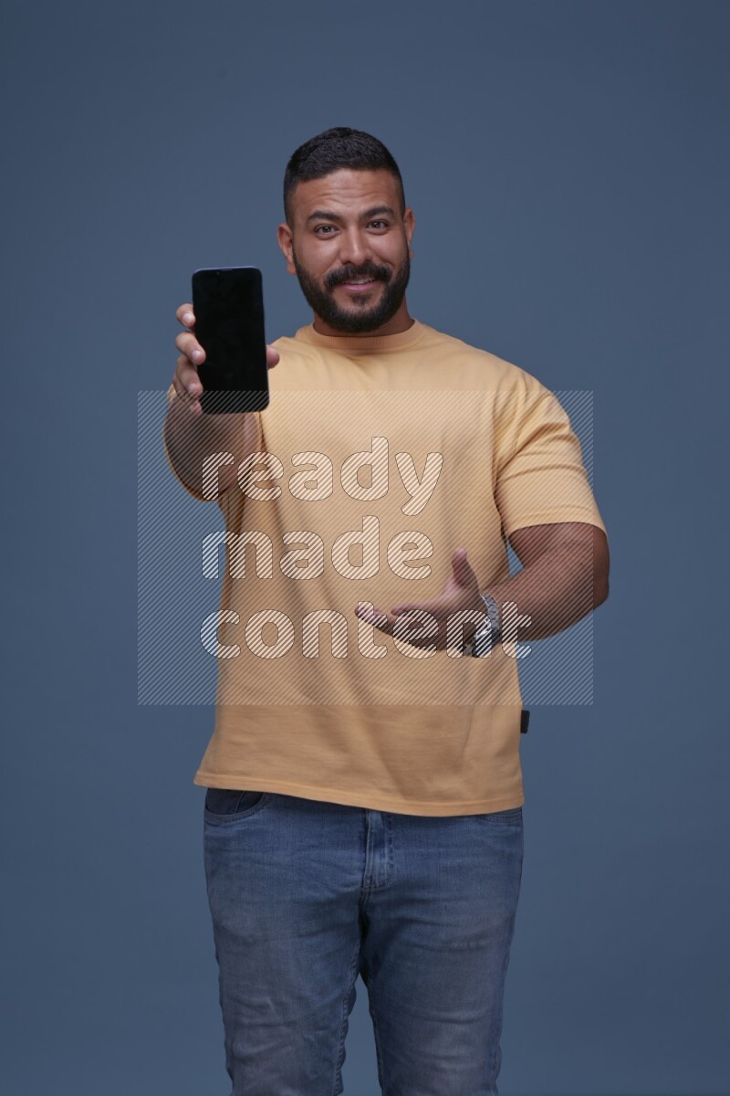 A man Showing His Smart Phone on Blue Background wearing Orange T-shirt