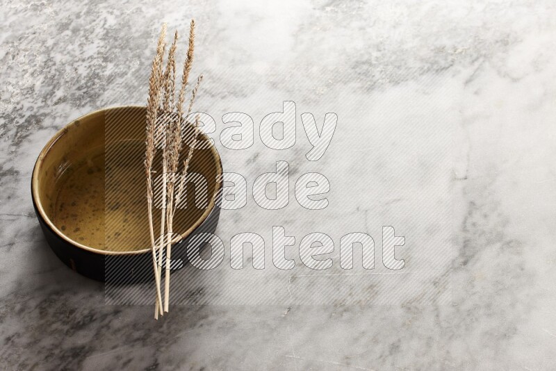 Wheat stalks on multicolored pottery oven plate on grey marble background