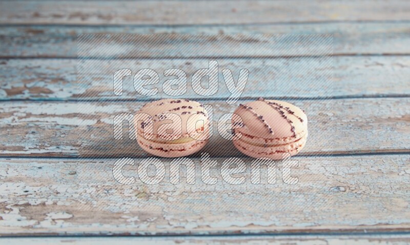 45º Shot of two pink orange blossom macarons on light blue wooden background