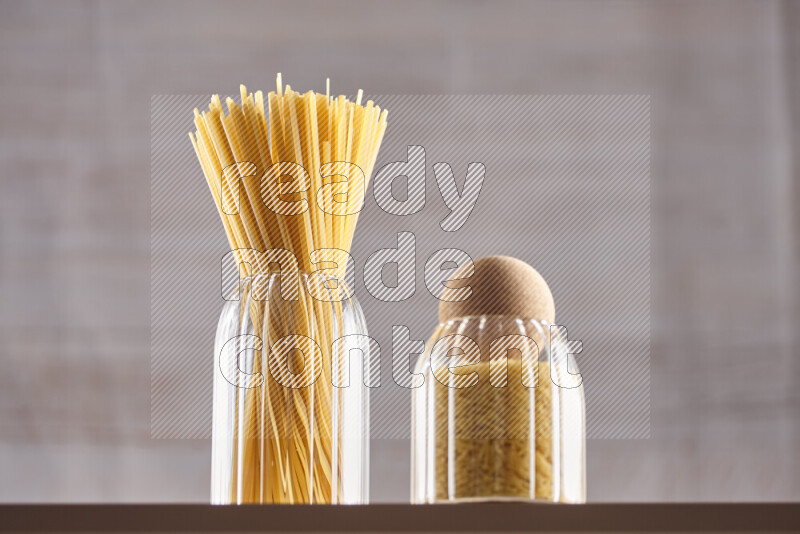 Raw pasta in glass jars on beige background