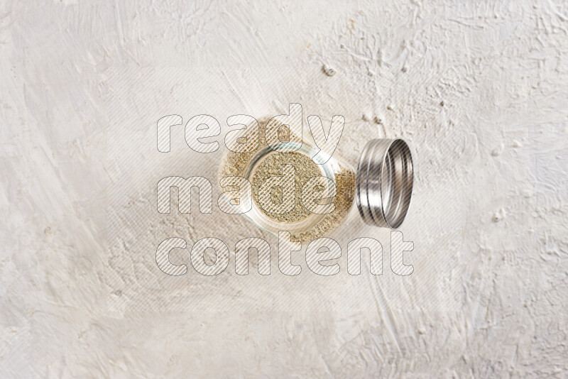 A glass jar full of ground ginger powder on white background