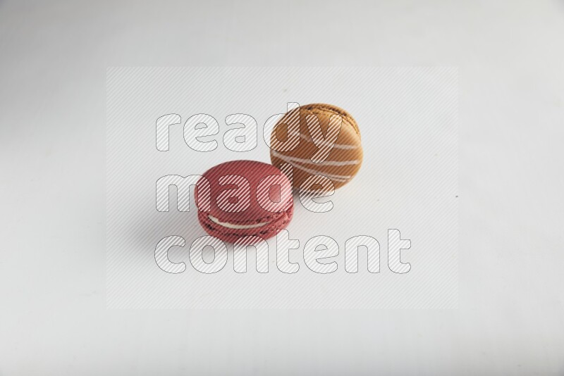 45º Shot of of two assorted Brown Irish Cream, and Red Velvet macarons on white background