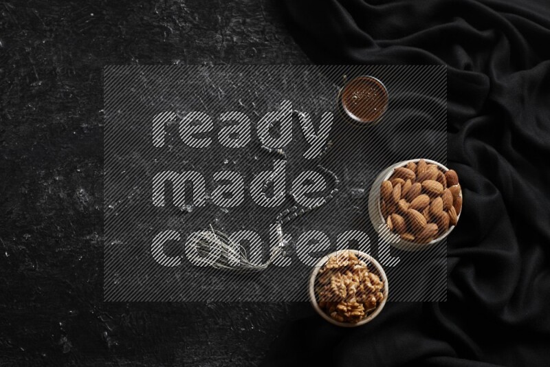 Nuts in pottery bowls with coffee in a dark setup
