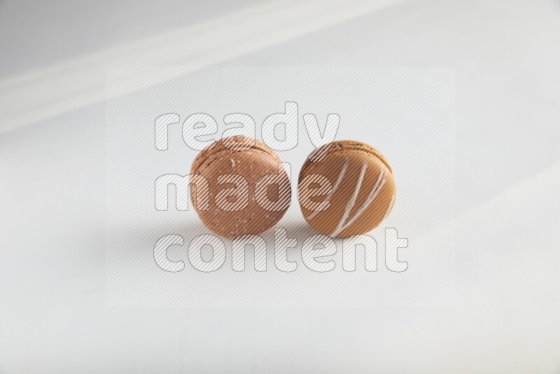 45º Shot of of two assorted Brown Irish Cream, and Brown Hazelnuts macarons on white background