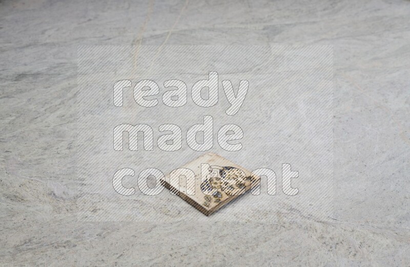 Top view shot of a pottery coaster\ tile on beige marble flooring