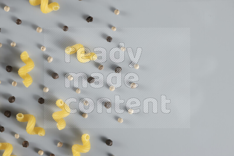 Raw pasta with different ingredients such as cherry tomatoes, garlic, onions, red chilis, black pepper, white pepper, bay laurel leaves, rosemary, cardamom and mushrooms on light blue background