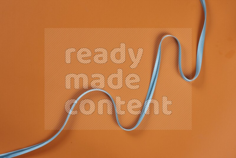 A blue collection of sewing and tailoring tools arranged on a orange background