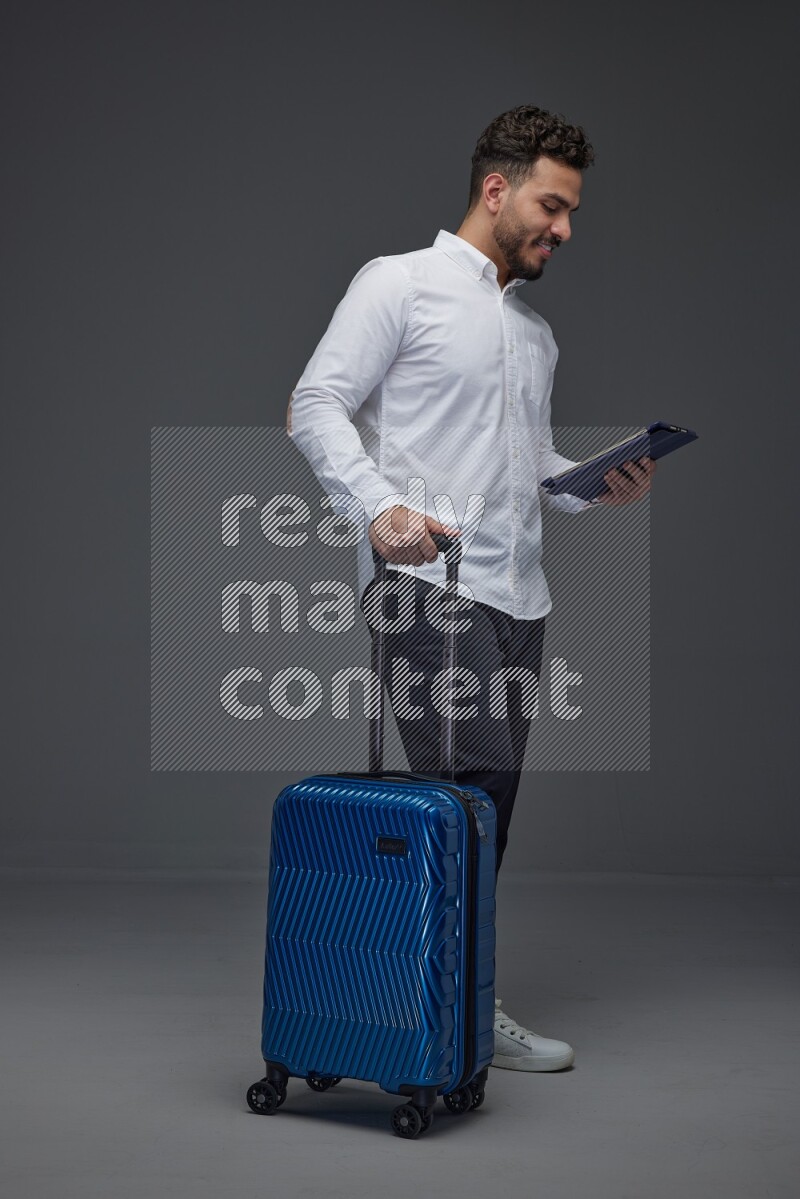 A man wearing smart casual with and pulling a carry-on luggage eye level on a gray background