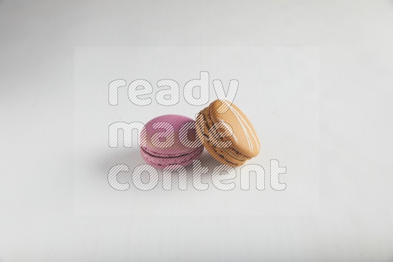 45º Shot of of two assorted Brown Irish Cream, and Purple Strawberry macarons on white background