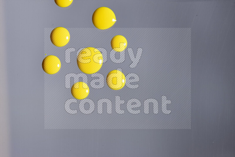 Close-ups of abstract yellow paint droplets on grey background