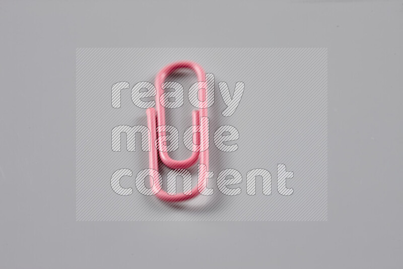Pink paper clips isolated on a grey background