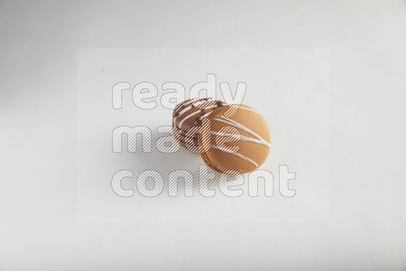 45º Shot of of two assorted Brown Irish Cream, and Brown white Chocolate Caramel macarons on white background