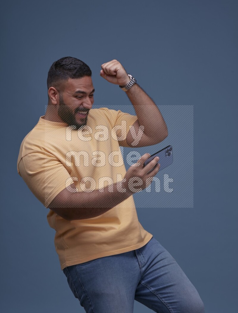 A man Playing Games on Smartphone on Blue Background wearing Orange T-shirt