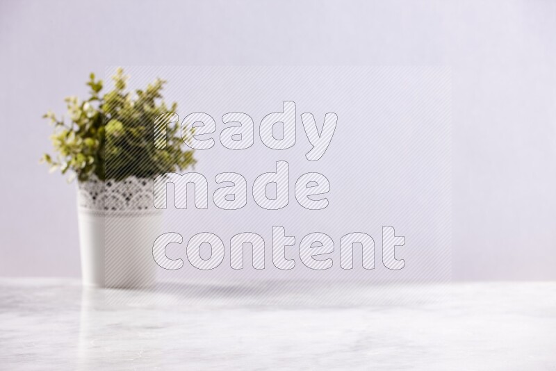 Artificial plant in white decorative pot on grey marble background