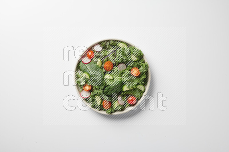 A bowl of fresh vegetables salad with kale leaves, cherry tomatoes, sliced radishes and sliced cucumber on a white background