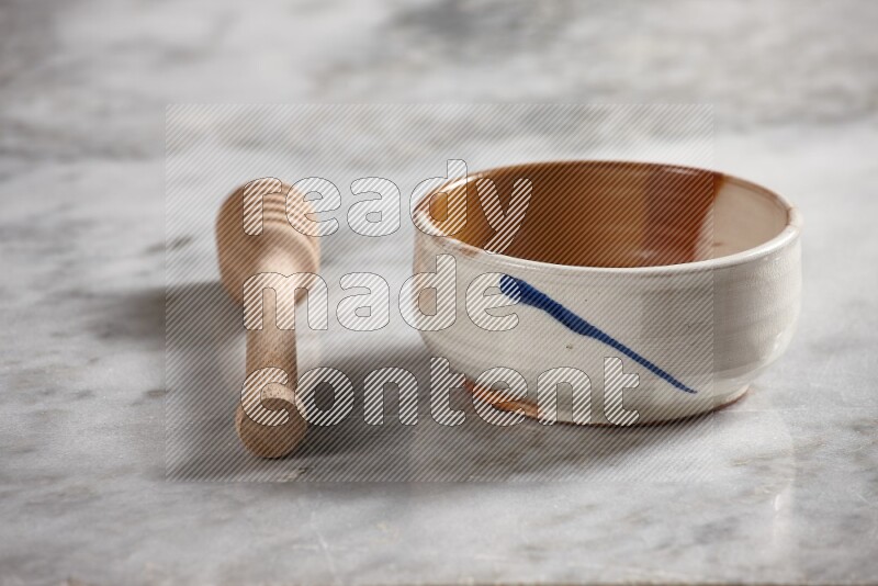 Multicolored pottery bowl with wooden honey dipper on the side on grey marble background
