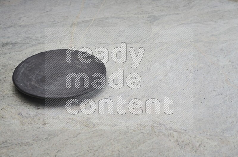 A black pottery plate on grey marble background