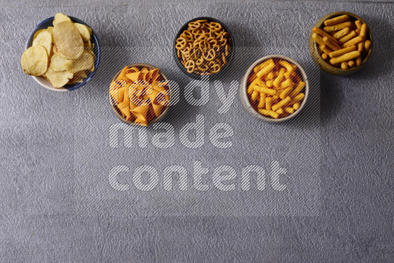 Assorted snacks in pottery bowls on grey background