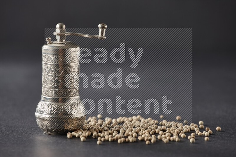 White pepper with a metal pepper grinder on black flooring