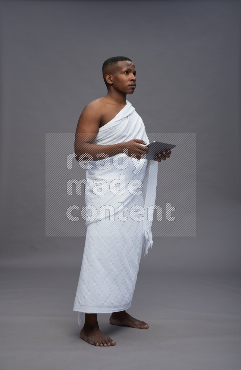 A man wearing Ehram Standing working on tablet on gray background