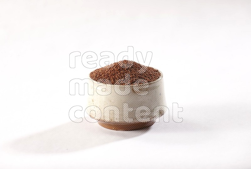 A beige pottery bowl full of garden cress seeds on a white flooring