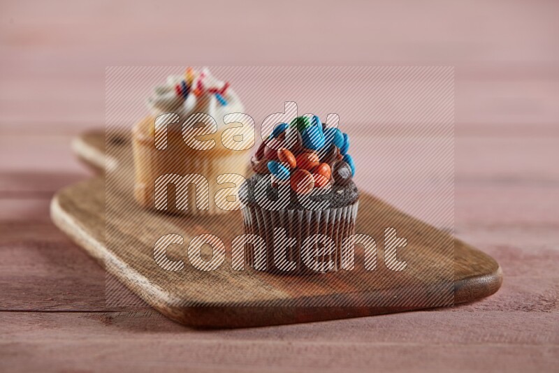 Chocolate mini cupcake topped with m&ms on a wooden board