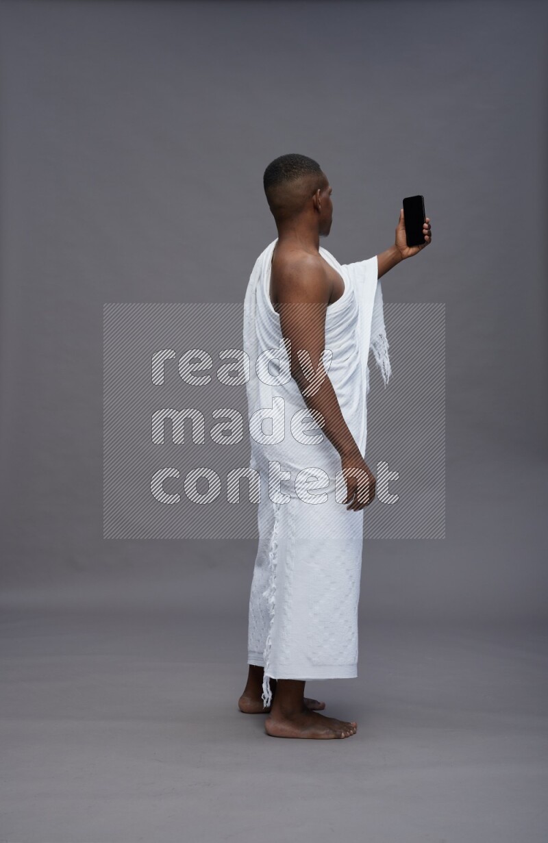 A man wearing Ehram Standing taking selfie on gray background