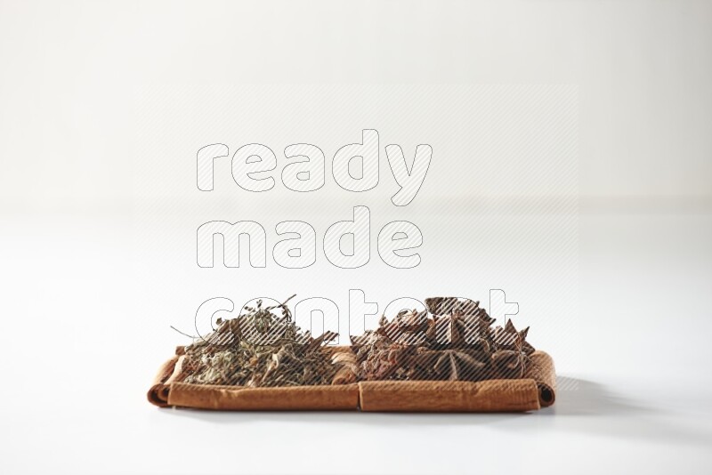 2 squares of cinnamon sticks full of star anise and dried basil on white flooring