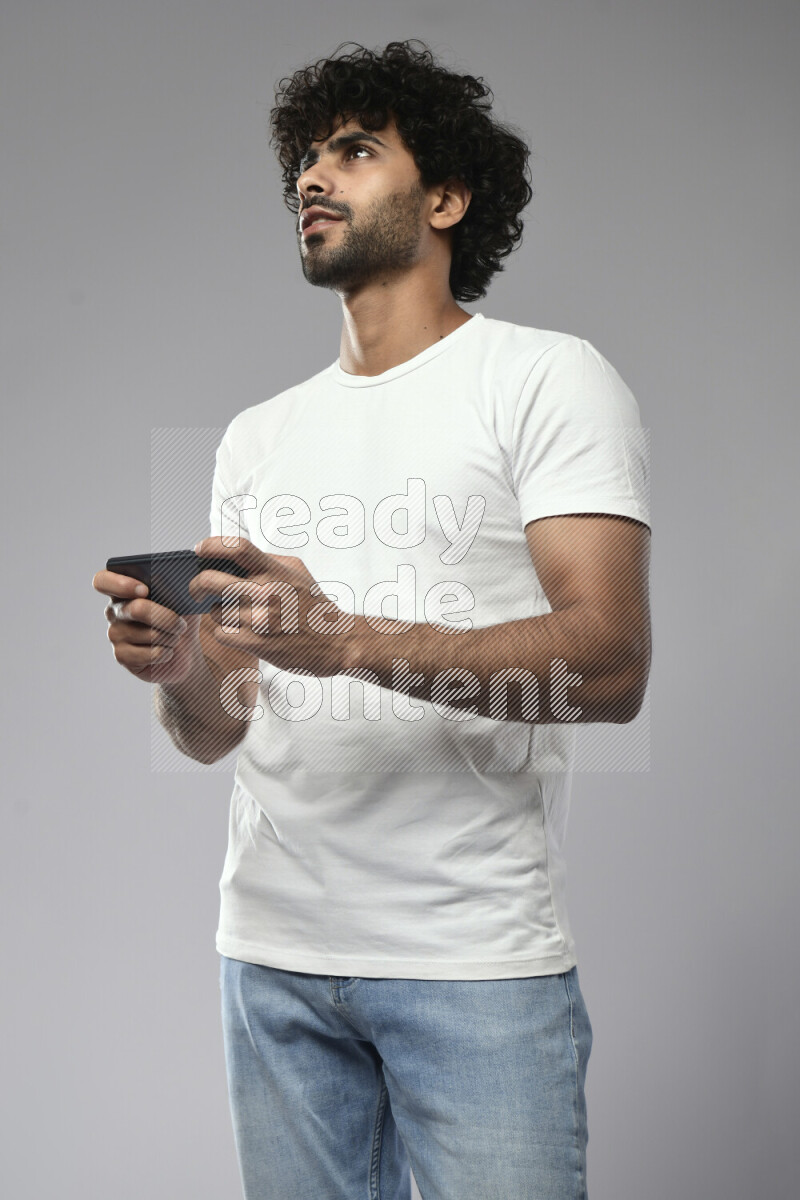 A man wearing casual standing and gaming on the phone on white background