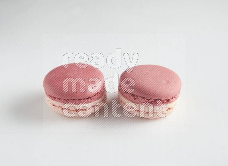 45º Shot of two Pink Litchi Raspberry macarons on white background