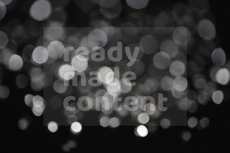 Silver shimmering fragments of glass scattered on a black background