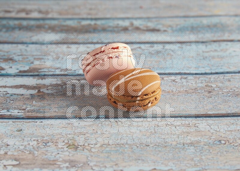45º Shot of of two assorted Brown Irish Cream, and pink orange blossom  macarons on light blue background