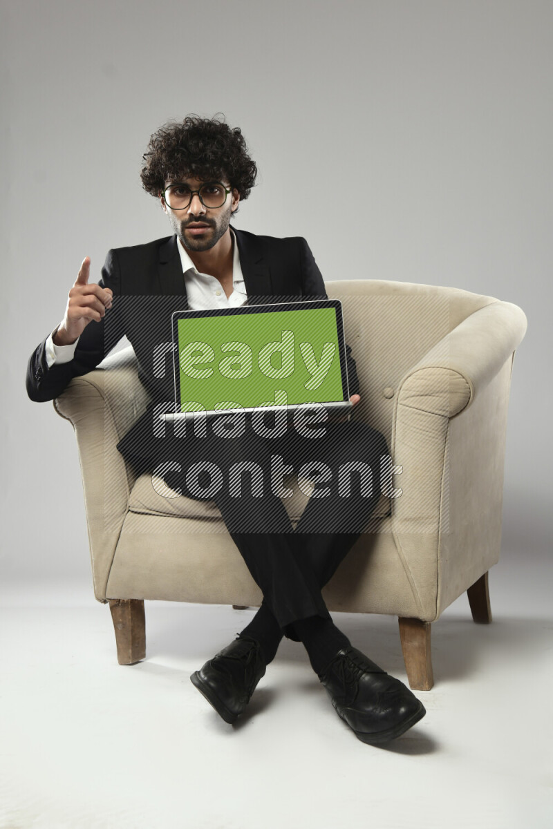 A man wearing formal sitting on a chair showing a laptop screen on white background