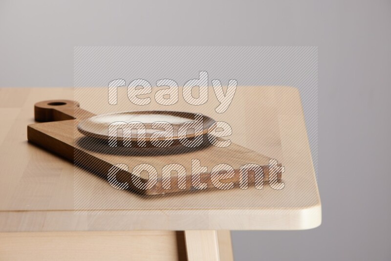 multi-colored pottery Plate placed on a  wooden rectangular cutting board on the edge of wooden table